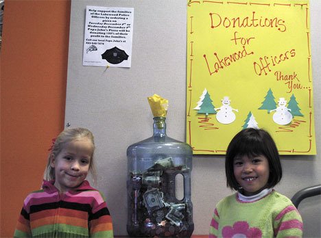 Kindergartners Ava Graff and Mia Pearl Rapp stand next to the jug that their school has helped fill. The money will be going for the families of the fallen Lakewood police officers.