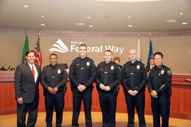 Mayor Jim Ferrell stands with four new police officers and Chief of Police Andy Hwang at the swearing in ceremony on Tuesday.