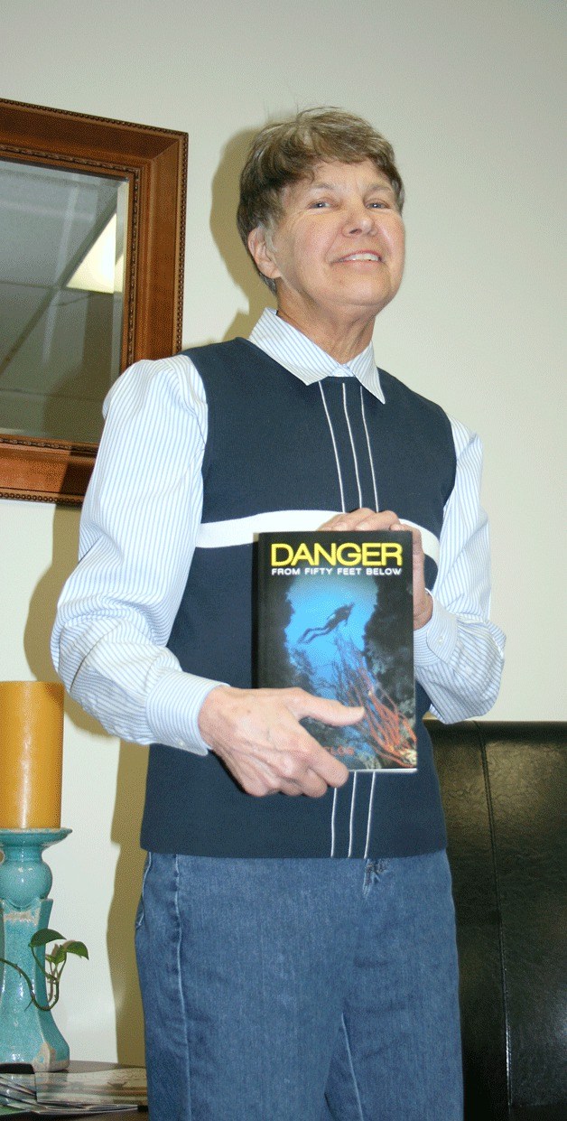 Federal Way City Councilmember Dini Duclos holds up her new book 'Danger from Fifty Feet Below