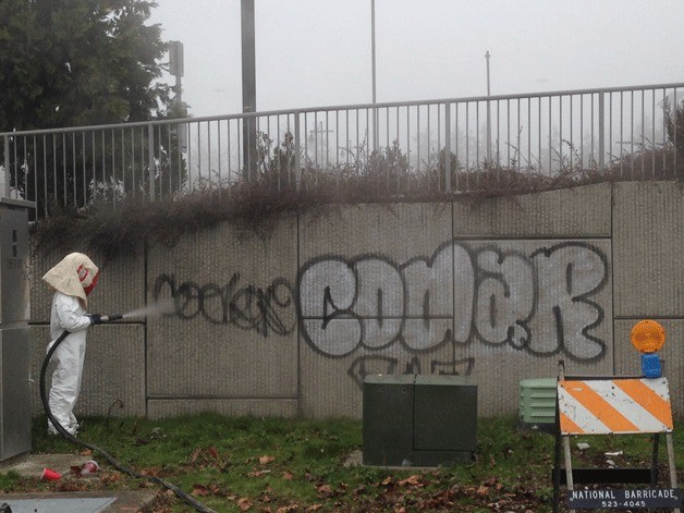 A city of Federal Way employee uses a sand blasting machine to remove graffiti from public property.