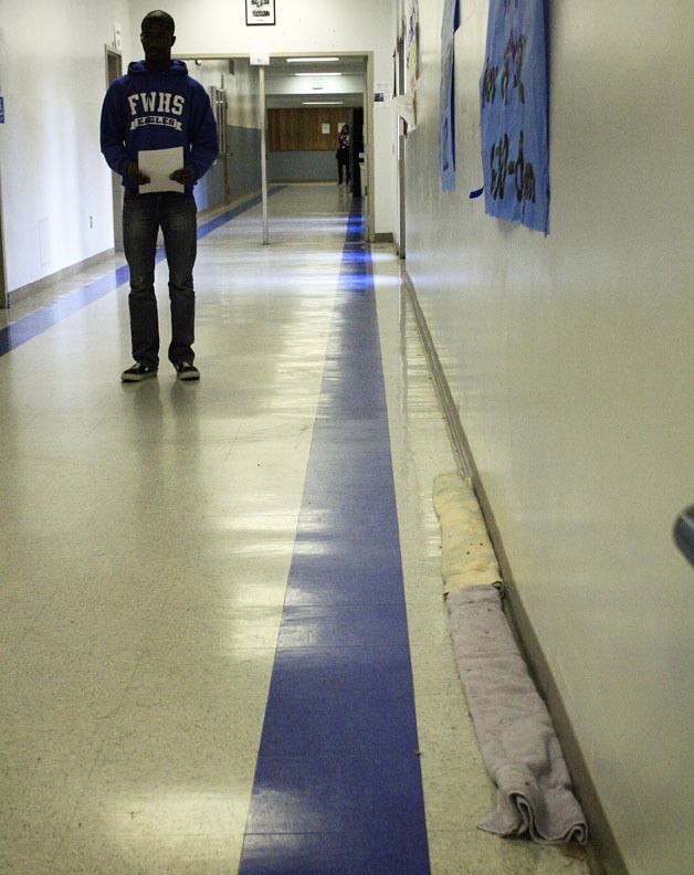 A student walks the halls of Federal Way High School in this November 2011 photo. Towels along the walls are used to combat significant leaks in the school's hallways.