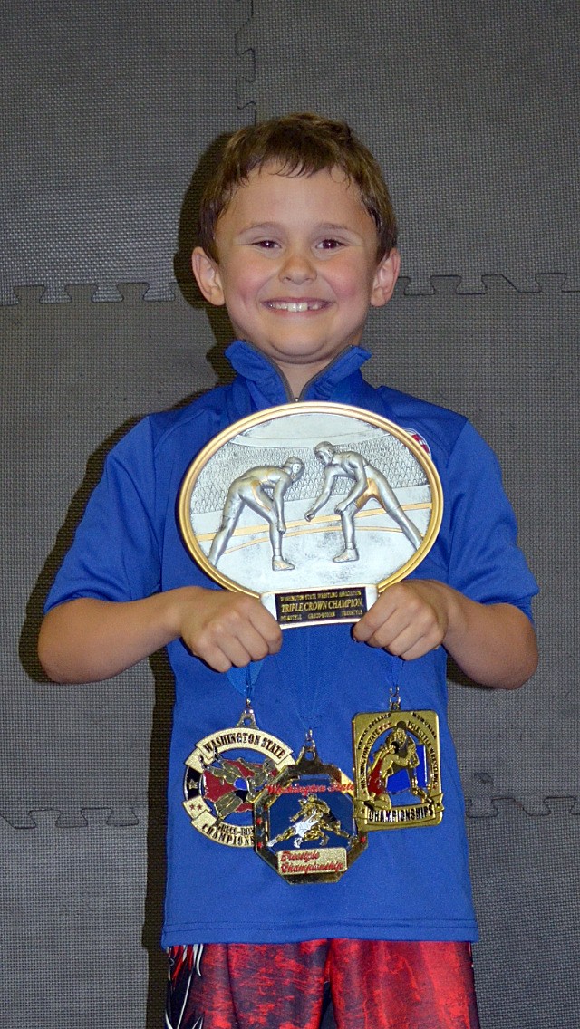 Nolan Gandert with his triple crown trophy and his state championship medals for folkstyle