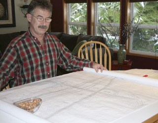 Gary Anderson sits at his kitchen bar as he looks over a map illustrating future construction of South 312th Street in connection with the City Center Access Project. Anderson's home is one of at least four that may be bought by the city and demolished to make room for a new roadway in 2010.
