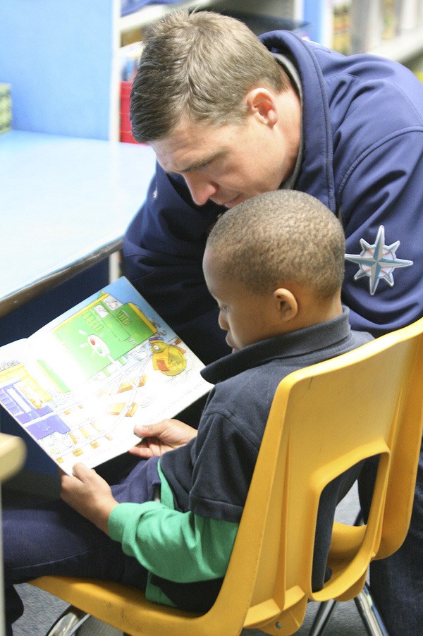 Mirror Lake Elementary first grader Keilian Butts reads a book while former Seattle Mariner catcher Dan Wilson looks on Tuesday morning. Wilson was at the school to promote literacy.