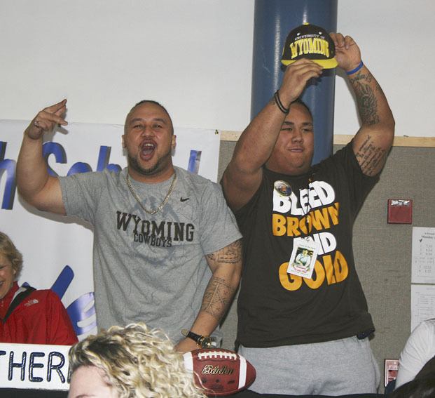 Federal Way senior Uso Olive (right) celebrates signing his national letter of intent to play football at the University of Wyoming with his older brother