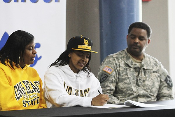 Federal Way senior Raven Benton signs her National Letter of Intent to play basketball at Long Beach State University Thursday morning while surrounded by her parents inside the Federal Way cafeteria.