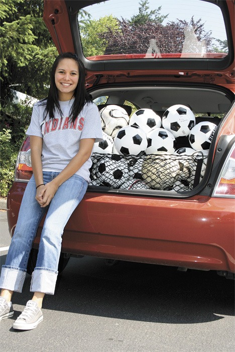 Bonney Lake High School senior Adriana Guzman poses in front of a trunk full of soccer balls she and her dad