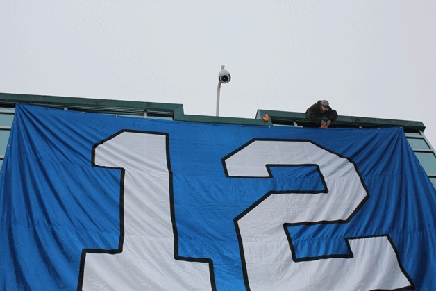 A worker adjusts a giant 12th man flag that will hang over Federal Way City Hall on Friday