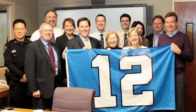 Federal Way Mayor Jim Ferrell and his management team display the 12th man flag at City Hall. The city invites residents to join city officials as they hoist the 12th man flag on Friday.