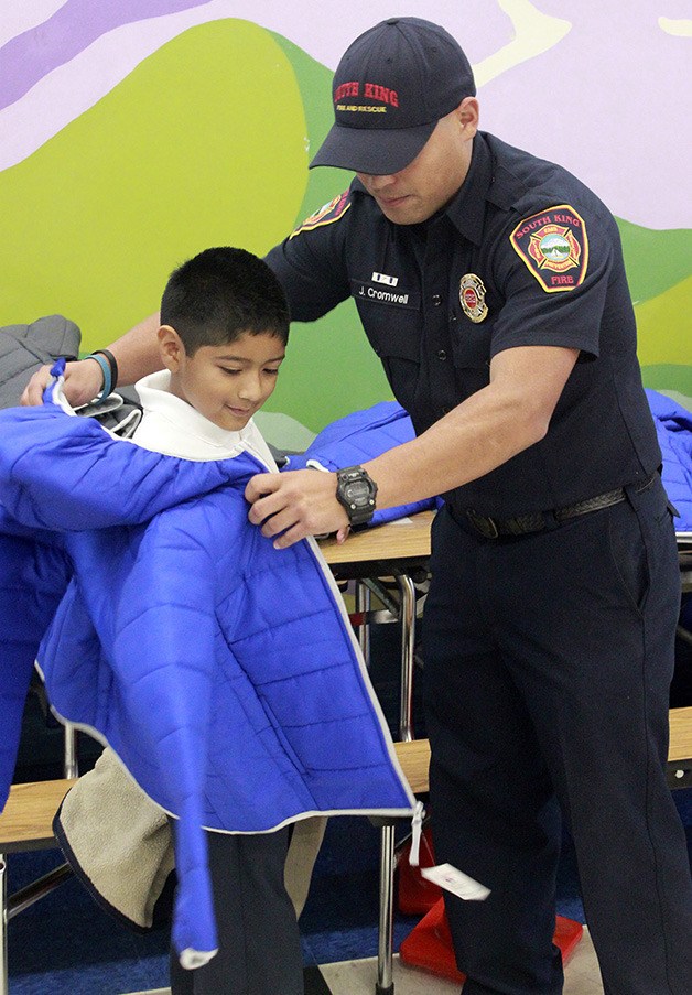 South King Fire's James Cromwell puts a new winter coat on third-grader Kevin Salinas at Olympic View Elementary. Federal Way police teamed with South King Fire and Rescue for Operation Warm. On Nov. 13