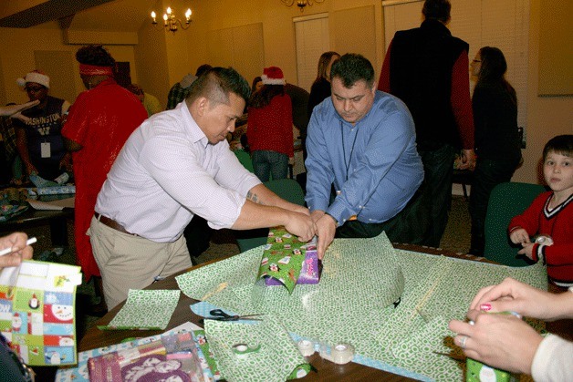 Volunteers Makara Chea (left) and Chuck Ceylan (right) wrap gifts during the Federal Way Police Department's annual Adopt-a-Family program at Grace Church on Friday. Chea and Ceylan are both employees at Cash America