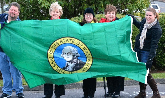 John Fairbanks and Diana Noble-Gulliford raised a new state flag that Rep. Linda Kochmar (second from left) donated to the Historical Society of Federal Way on Saturday.