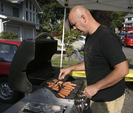 Steve Potter works the grill during his neighborhood's National Night Out event on Tuesday. 'It's perfect timing