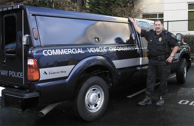 Officer Manny Mairs stands in front of the commercial vehicle enforcement patrol truck. Police began enforcing commercial vehicle regulations in Federal Way in September.