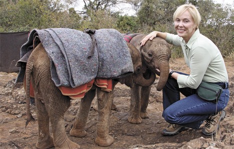 Becci Crowe kneels with two baby elephants at the David Sheldrick Wildlife Trust in Kenya. The babies’ mothers were killed by poachers