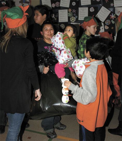 Mary Longoria holds Haley Hernandez and a bag of gifts Friday at the Adopt-A-Family event at Adelaide Elementary School.