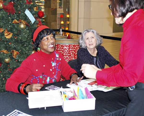 Volunteers Rose Ratteray and Billie Paddock help an interested shopper at The Giving Tree in The Commons Mall. Shoppers select tags with gift ideas