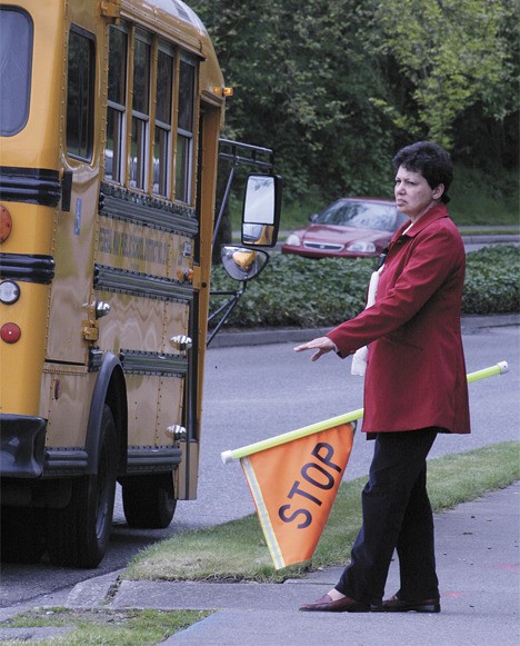 Panther Lake Elementary crossing guard Bev Duncan waves a flag and gives hand motions May 14