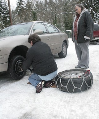 Gary Walkama changes a flat tire for his friend Cheri Davidson on Tuesday at the 7-11 parking lot on 1st Avenue South in Federal Way. 'That's what Christmas is all about