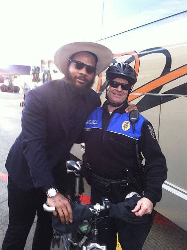 Federal Way police officer John Stray (right) poses with Seahawks defensive end Michael Bennett during a send-off parade on Sunday. Bennett surprised Stray when he asked the officer to borrow his bicycle and rode a lap around some buses.