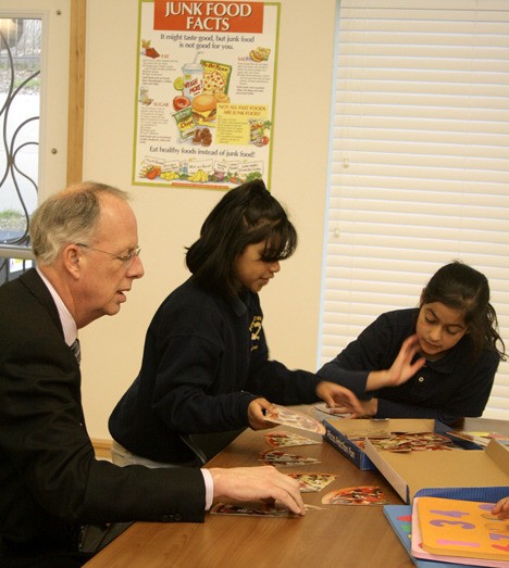 Federal Way Mayor Skip Priest takes a break to play educational games with children at the Appian Way apartment complex in Kent. Priest was participating in a tour of affordable housing in the area. The children were participating in Appian Way's homework club.