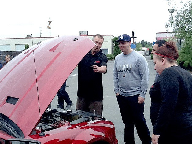 Bob Bjorneby (left) describes what his team did to remodel David Padilla's (center) Ford Mustang to fulfill the teen's wish through the Make-A-Wish Foundation at Bob Bjorneby's Federal Way CARSTAR Collision on Wednesday. Padilla has stage 4 bone cancer.