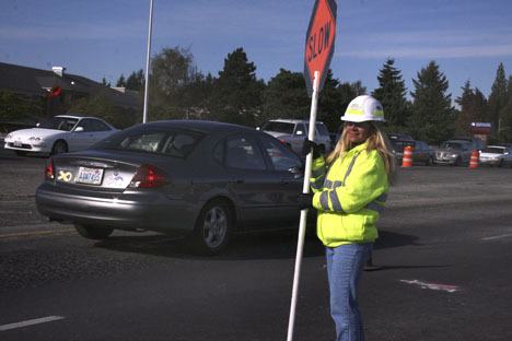 A flagger with construction company J.R. Hayes and Sons Inc. warns motorists to slow down Monday on Pacific Highway South in front of Federal Way High School. After 10 years