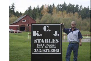 Ken Culliton stands in front of a sign for his farm