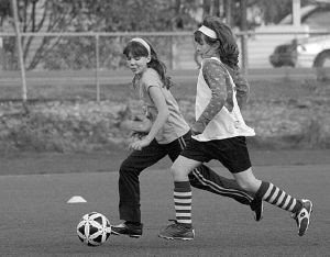 Kellie Twitchell (left) and Kylie Miller go after the soccer ball at a recent practice for the under-11 Gold Reign ‘97 select girls soccer team at Steel Lake Park. The Gold Reign is a member of the Federal Way United Soccer organization. Hundreds of Federal Way kids play on field around the city. The Gold Reign is coached by Joe Jordan.