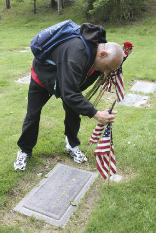 Max Flint of Tacoma places U.S. flags at the graves of veterans on Memorial Day at the Gethsemane Cemetery in Federal Way. After paying his respects to his own loved ones