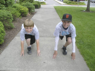 Enterprise Elementary School fifth-graders Dax Wallat (left) and Christian Stafford do some stretches before completing another 25 Mile Club lap.
