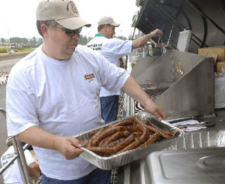 Volunteer Scott Alleman takes the first batch of Johnsonville Brats off the ‘World’s Largest Grill Period’ at the Emerald Downs horse racing track in Auburn last weekend. The ‘World’s Largest Grill Period’ was at Emerald Downs as a fund raiser to benefit local charities. Weighing more than 53