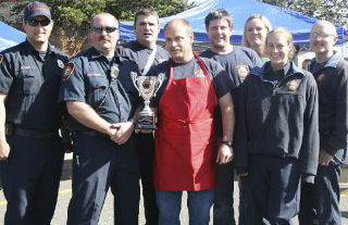 Jeff Hamel holds the first-place trophy for South King Fire and Rescue’s Station 62 Shark Pit team at the inaugural Federal Way Farmers Market Chili Cook-off on Saturday. The team also won the people’s choice award. Federal Way police and South King Fire and Rescue firefighters battled for chili supremacy in an event that raised money for South King Firefighters Foundation as well as Special Olympics.