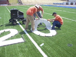 Workers install the 20-yard line marker at the football/soccer field at Federal Way Memorial Stadium recently. The new grass-like Field-Turf replaced the old turf