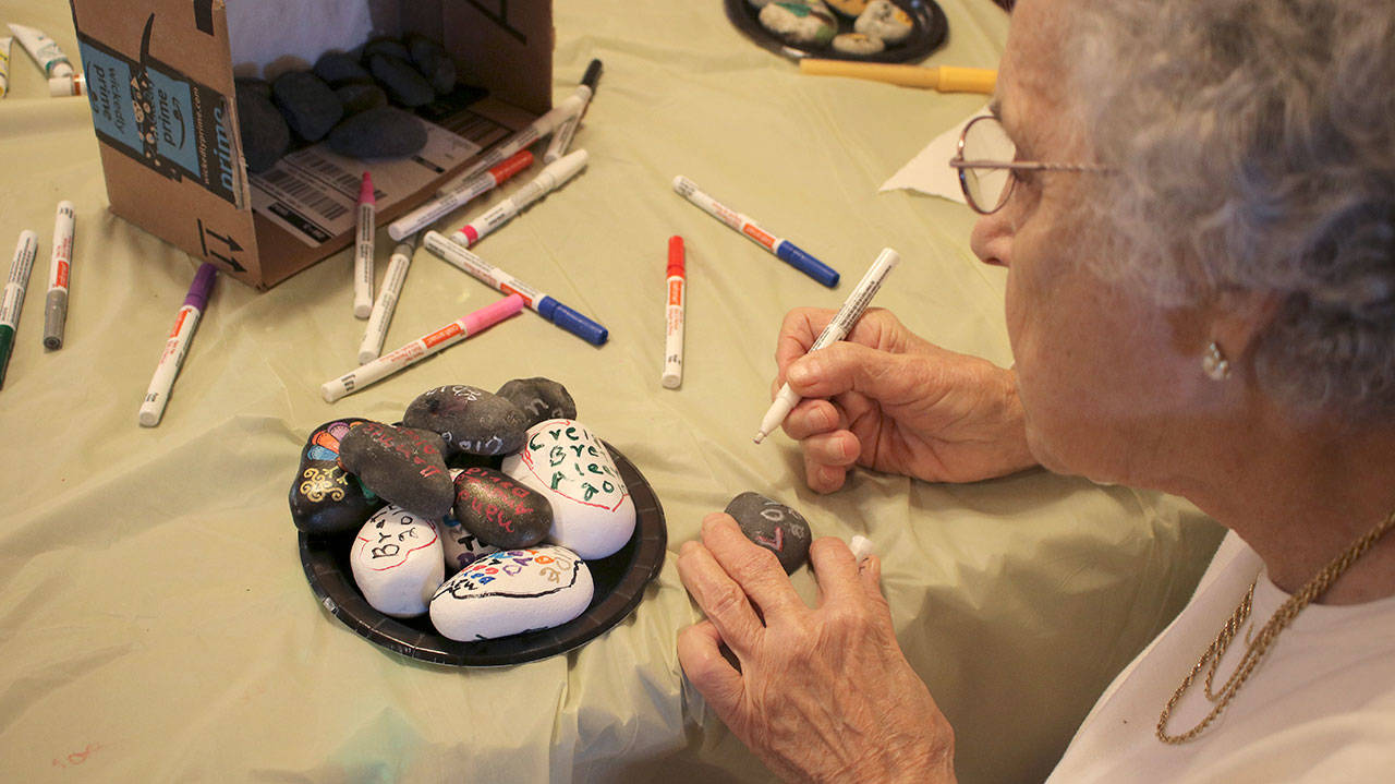 Leora Kuwitzky, 88, uses a paint pen to write the names of her grandchildren on rocks during the Federal Way Rocks event at Brookdale Foundation House. This event helped bring older and younger generations closer together. Courtesy Miasmin Andre, UW News Lab