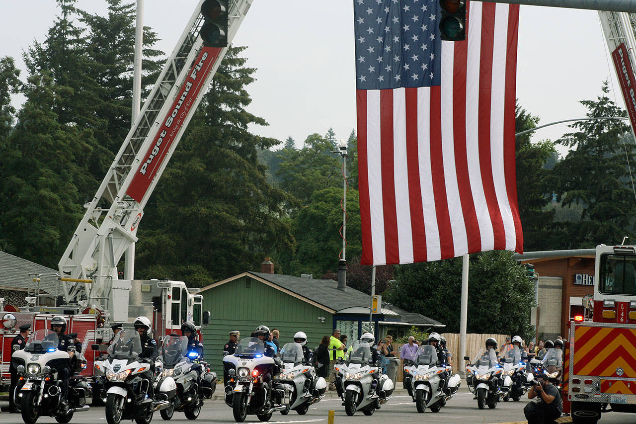 Police motorcyclists go under a flag displayed Tuesday along West James Street during a procession for Kent Police Officer Diego Moreno. STEVE HUNTER, Kent Reporter