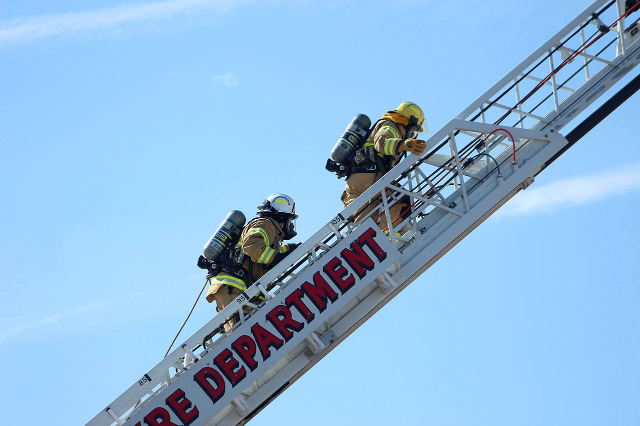 An attendee and their shadow climb a ladder wearing SCBA packs at Fire Ops 101. Olivia Sullivan/staff photo
