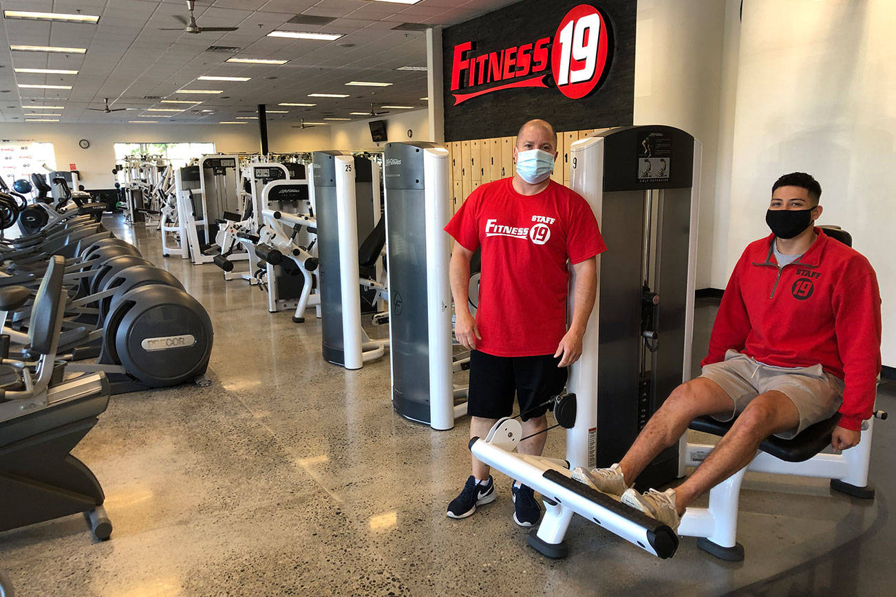 Fitness 19, located next to Fred Meyer, is among Federal Way gyms that are open for business with social distancing measures in place. Pictured: Staff members Ed Garberg, left, and Agustin Estrada. Andy Hobbs/staff photo