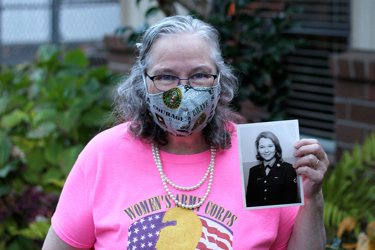 Torry Hemmert holds a photo of herself taken while she was in the army while wearing one of her handmade masks. Photo courtesy of her son, Jon Hemmert