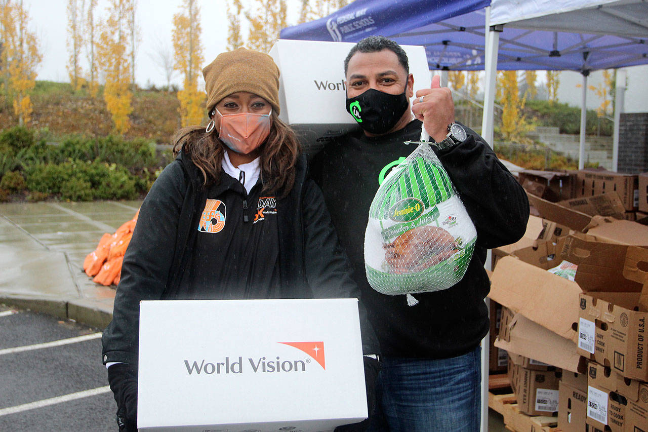 World Vision Corporate Engagement Director Samantha King, left, and Chip-in Founder Gerald Smiley pause for a photo while providing turkeys, fresh food kits, PPE and school supplies to more than 300 local families at Federal Way High School on Nov. 23. Olivia Sullivan/the Mirror