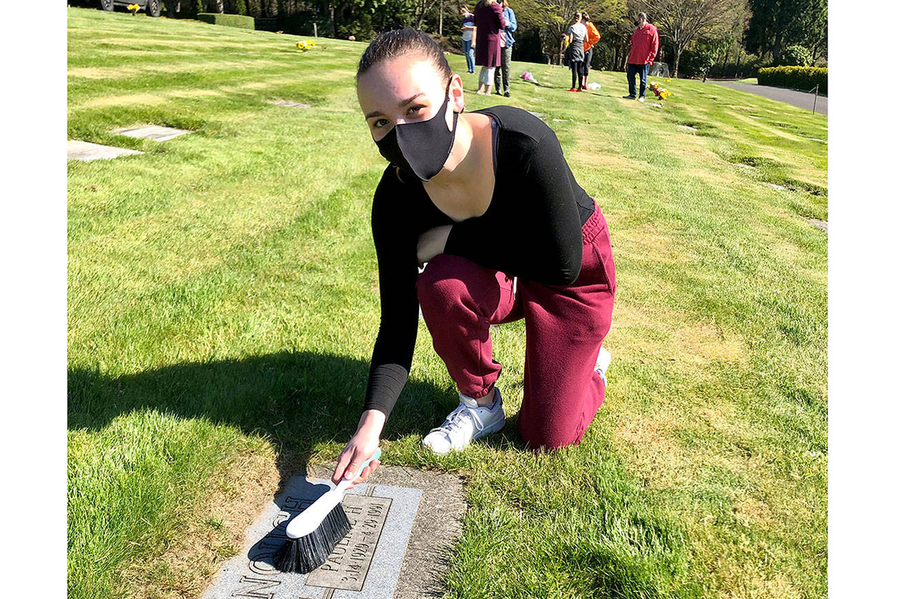 Emma Monson cleans a grave on April 17 in preparation to upload a photo of the grave to BillionGraves. Photo courtesy of Sheryl Mackey