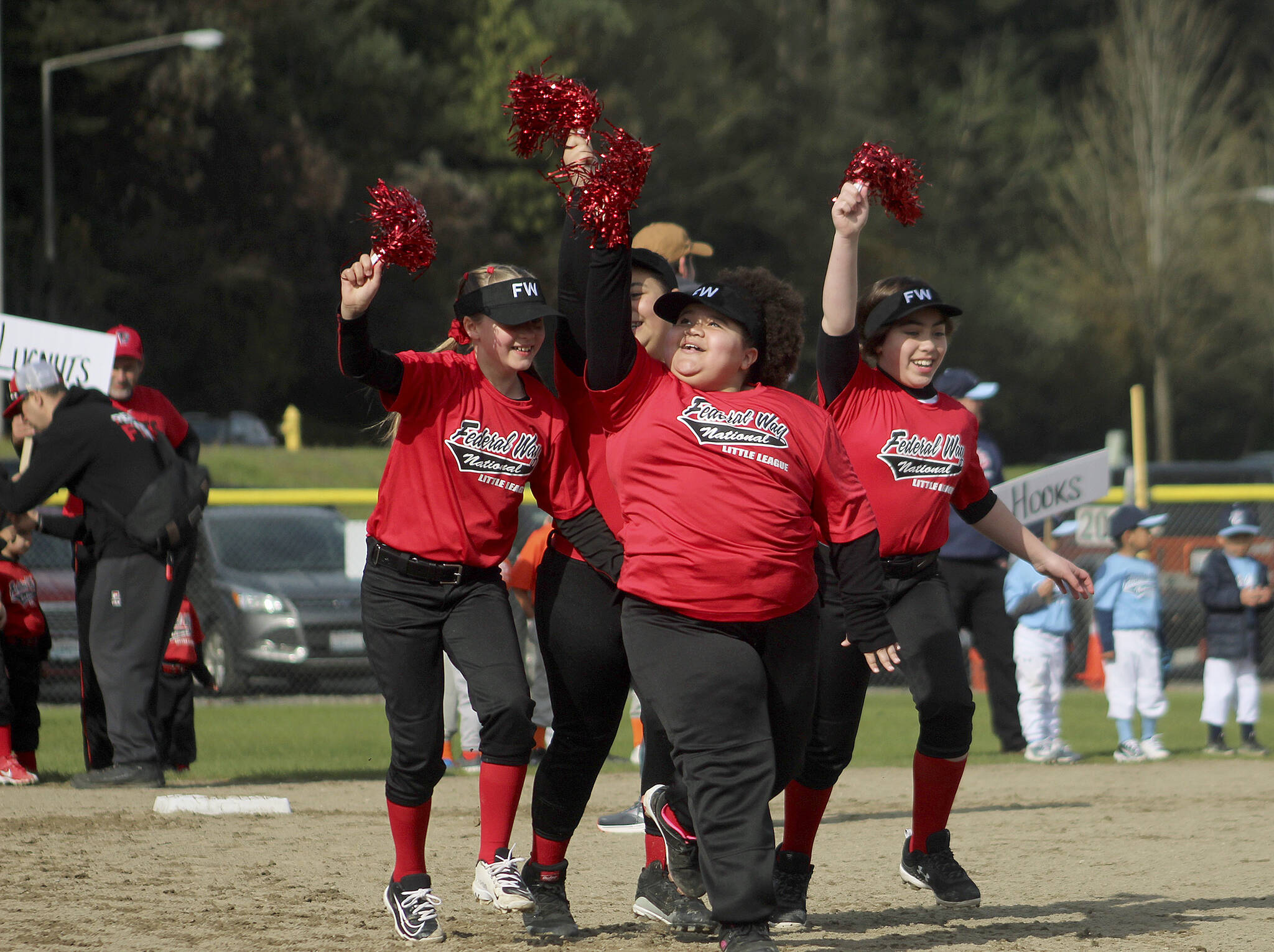 Fastpitch players carry sparkly pompoms as they run the bases on April 23. Olivia Sullivan/the Mirror