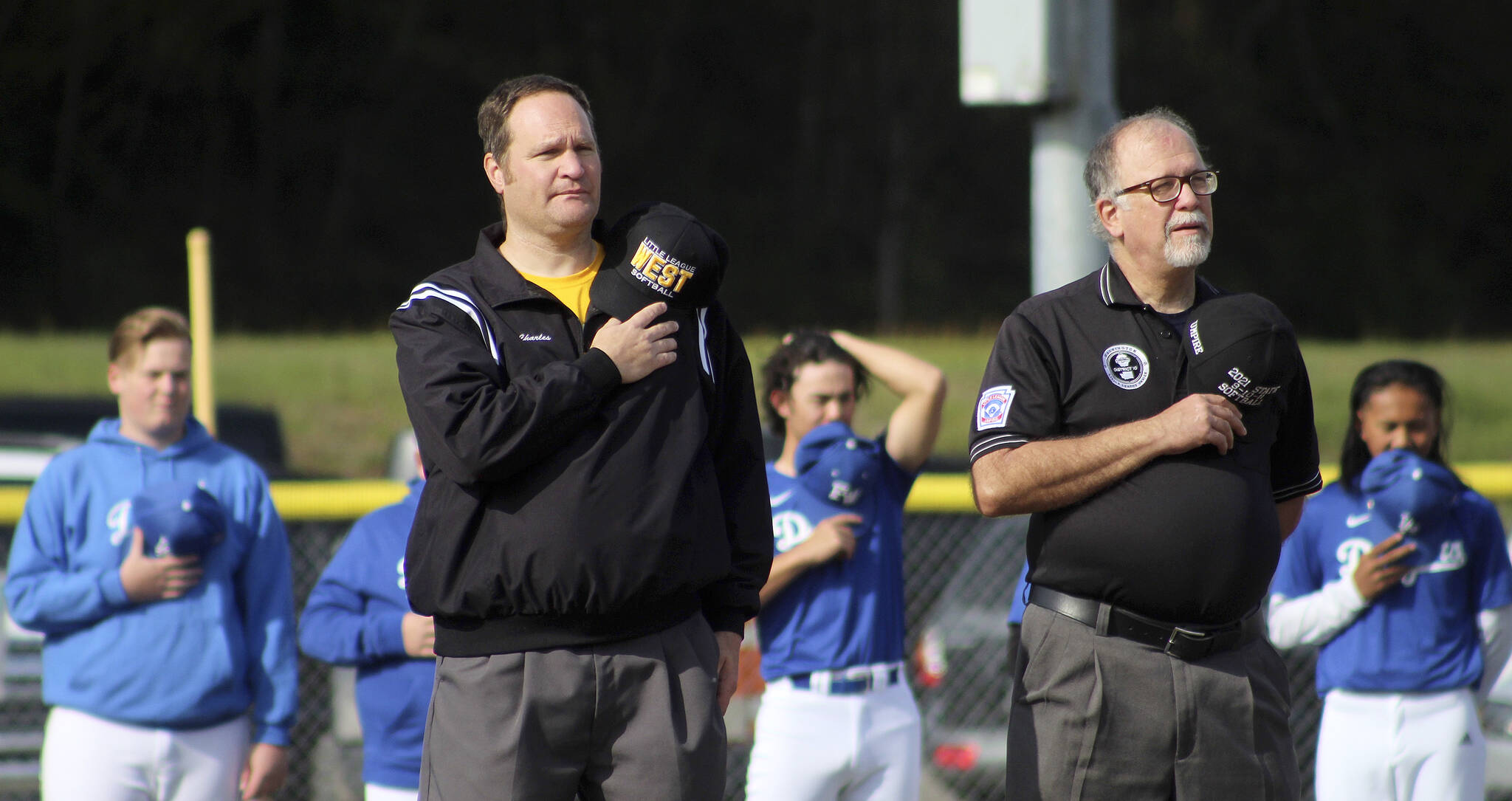 Federal Way National Little League President Charles Heitman, left, and Umpire in Chief Phillip Clark place their hats over their hearts during the National Anthem on April 23. Olivia Sullivan/the Mirror