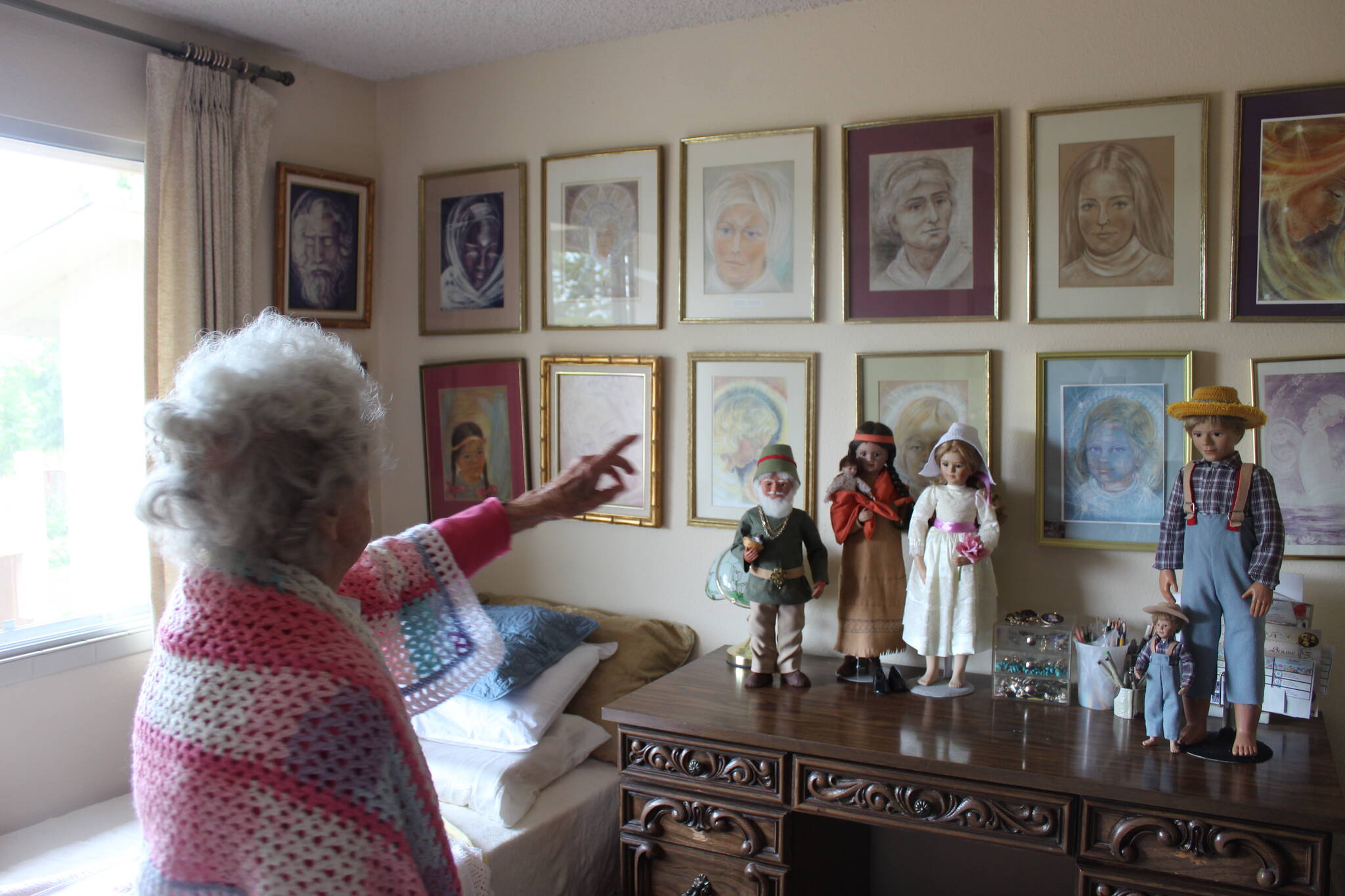 Wearing a shawl she crocheted herself, Irene Graham shows her impressionist art and some of her porcelain dolls that she made herself. Photo by Bailey Jo Josie/Sound Publishing