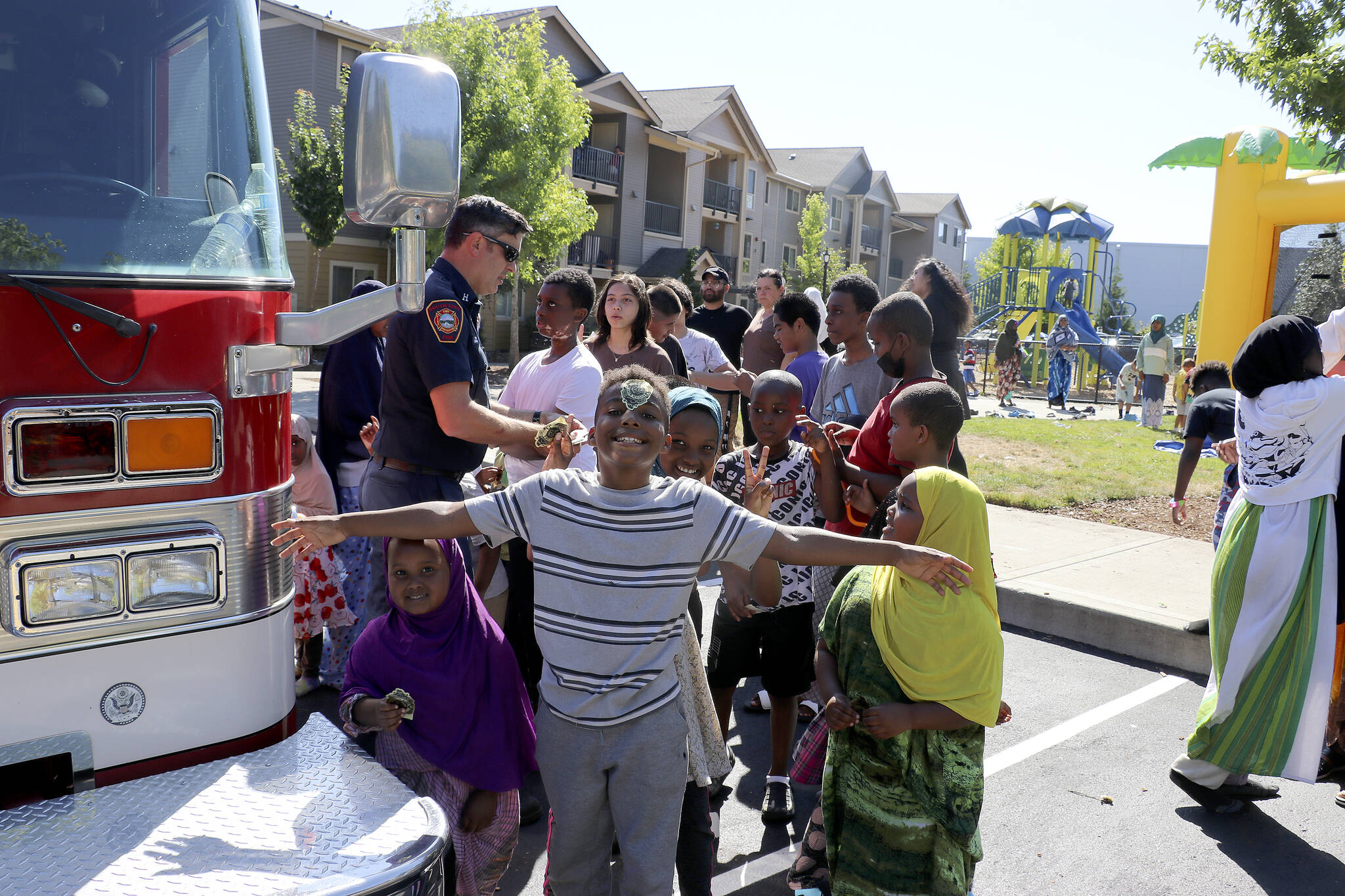 Capt. Brad Chaney hands out fire helmets and sticker badges to kids at the Kitt’s Corner Apartments on Aug. 2. Photo by Jack Reale