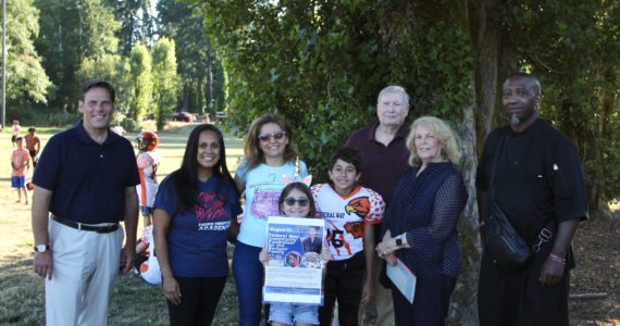 Marwa Almasri, center in blue, accepted a $1,000 donation on behalf of Jay Barbour on Aug. 16. The donation funds were collected by community donations and a portion of sales from K.C. Deez BBQ. From left: Mayor Jim Ferrell; Eileen Wilson of Pacific Christian Academy; Marwa Almasri and her daughter, Nai Barbour and her son, Majed Barbour; Rose Ehl of the Federal Way Farmers Market and her husband, Dave; and K.C. Deez BBQ owner De Davis. Olivia Sullivan/the Mirror