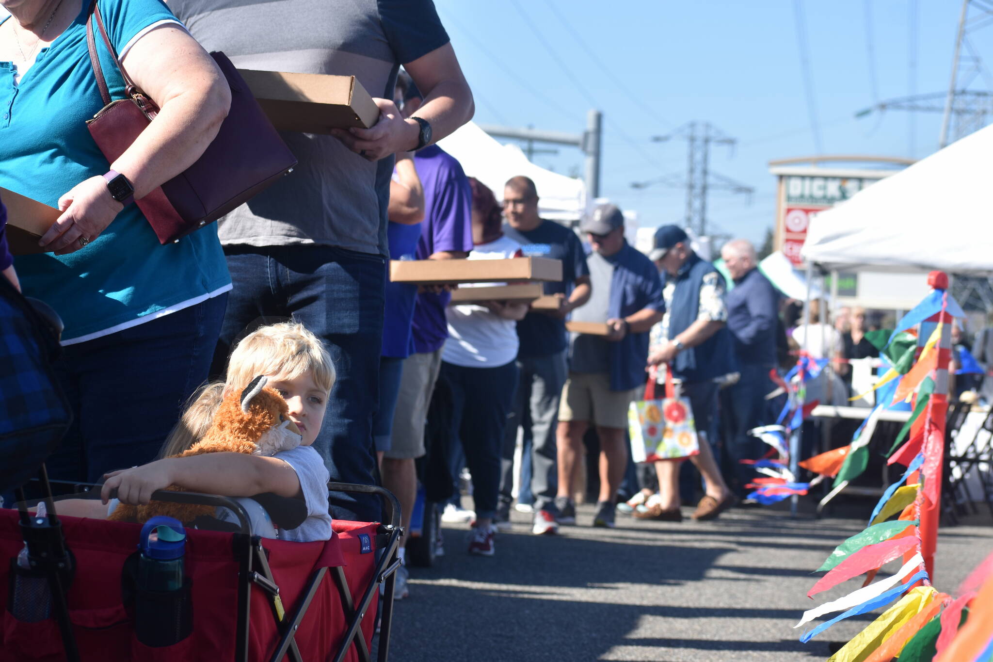 A kid shares a contemplative glance with their stuffed animal while the line makes its way through the restaurants at the Taste of Federal Way.
