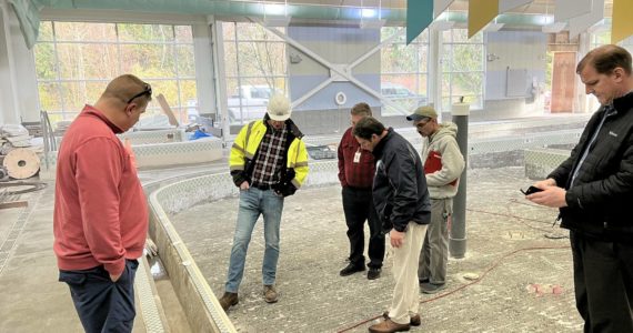 Federal Way Mayor Jim Ferrell and several others survey the work underway at the leisure pool on Dec. 9, which will need additional time for repair due to the discovery of corrosion in the concrete and rebar underneath its tiling. Photo courtesy of the City of Federal Way