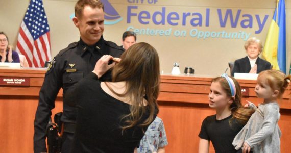 The family of Federal Way Police Officer Jeffrey Mundell pin his badge during his promotional swearing-in at the city council’s Jan. 17 meeting. Mundell was promoted from corporal to the lieutenant position. Alex Bruell / The Mirror