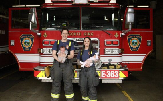 South King Fire and Rescue Lt. Ann Hoag, left, holds her son Flynn and firefighter Amanda Weed holds her daughter, Parker, in the engine bay of Station 63 on March 9, recreating a photo the two took months before while pregnant. Olivia Sullivan / The Mirror